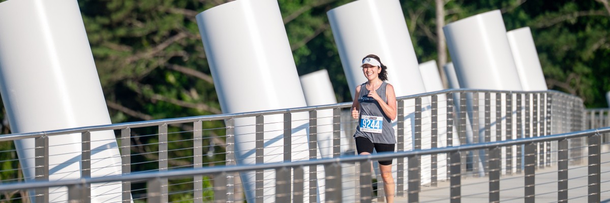 A racer smiles while running in the PCOM Georgia Old Peachtree Blaze 5K