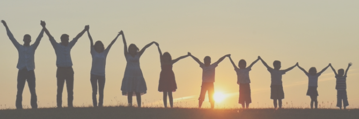 Silhouettes of adults and children holding hands with arms raised at sunset